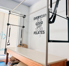 Grupo pequeno de três pessoas praticando Pilates em tapetes em estúdio moderno